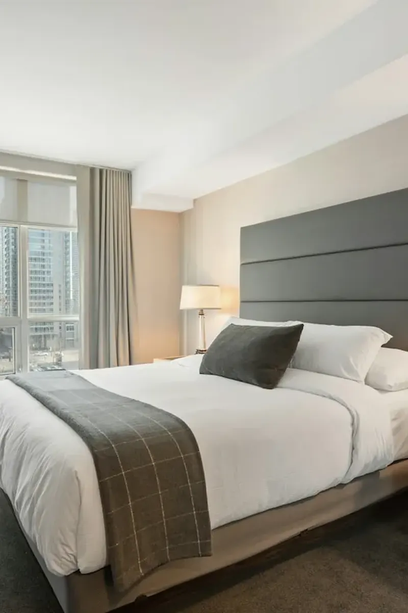 Cozy bedroom with layered linen bedding, warm bedside lamp and natural wood nightstand